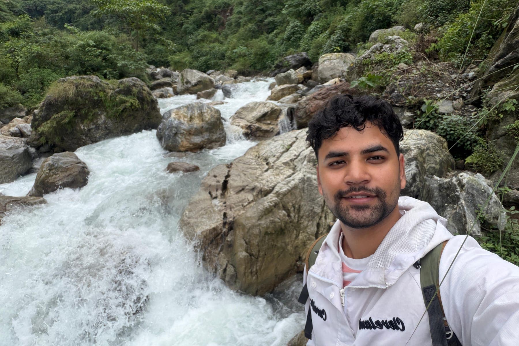 Selfie of Tarush beside a fast mountain river and boulders